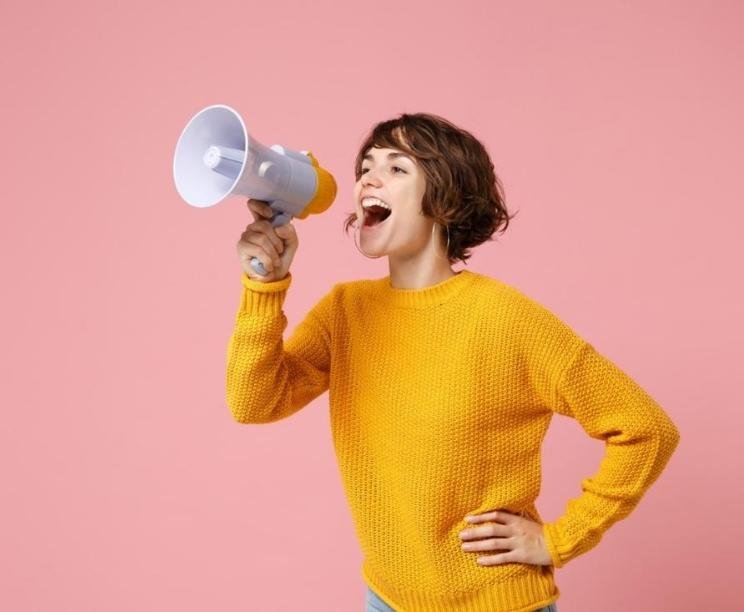 woman girl in yellow sweater announcing through megaphone